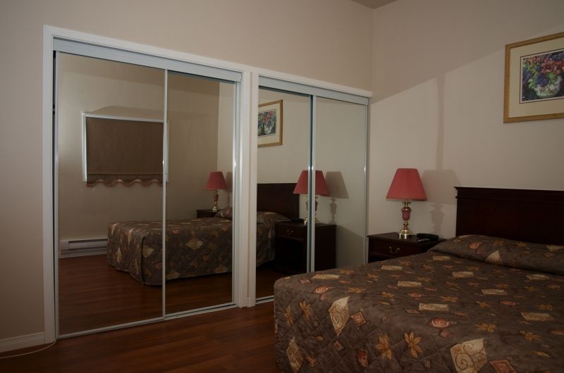 A bedroom with two beds and a large mirrored closet