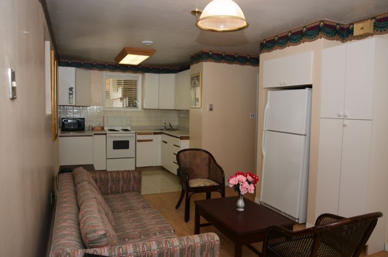 A living room with a couch and chairs and a kitchen
