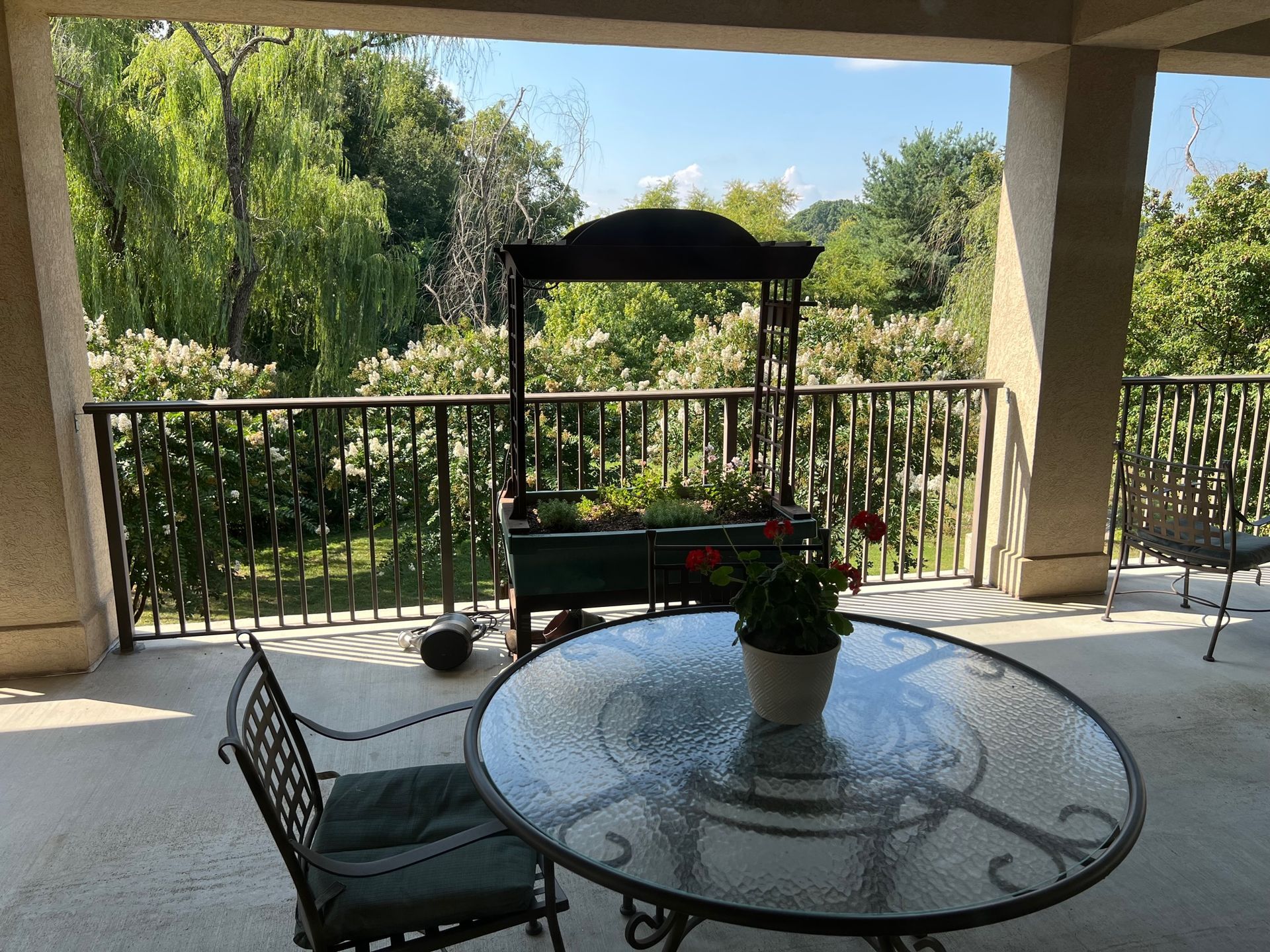 There is a table and chairs on the porch with a view of the trees.