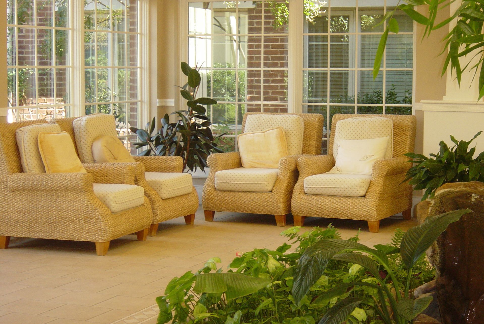 A living room with wicker furniture and lots of windows