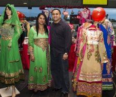 A man and a woman are standing in front of mannequins in a store.