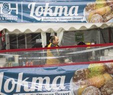 A man is standing in front of a sign that says tokma on it.