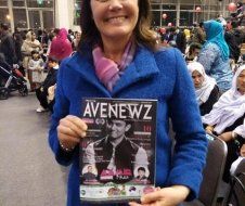 A woman in a blue coat is holding a copy of avenewz