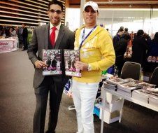 Two men are standing next to each other holding magazines.