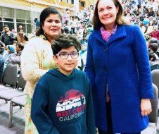A woman and a boy are posing for a picture in front of a crowd.