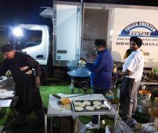 A group of men are cooking food in front of a truck.