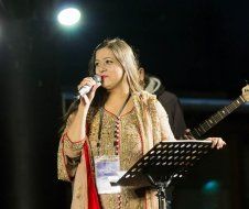 A woman is singing into a microphone on a stage.