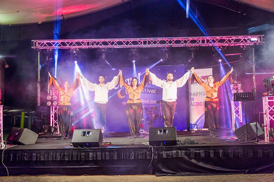 A group of people are standing on a stage holding hands.