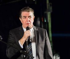 A man in a suit and tie is holding a microphone in his hand.