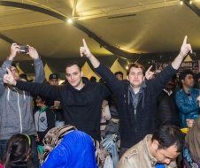 A group of people are standing in a room with their arms in the air.