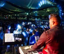 A man is playing a keyboard in front of a crowd at a concert.