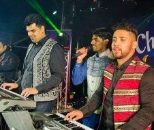A group of men are playing keyboards and singing into microphones on a stage.