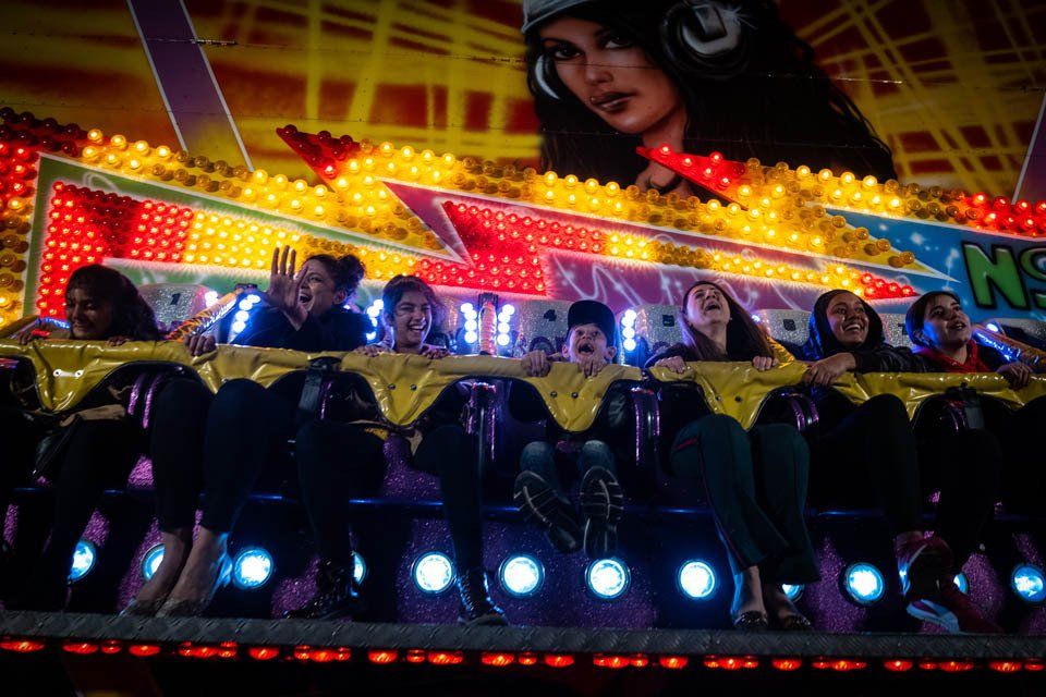 A group of people are riding a roller coaster at a carnival.