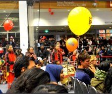 A crowd of people are gathered in a room with balloons hanging from the ceiling