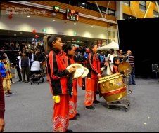A group of people are playing drums in front of a crowd