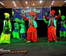 A group of people are dancing in front of a banner that says chand raat