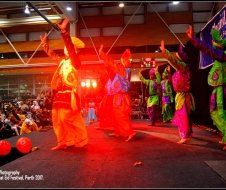 A group of people in colorful costumes are dancing on a stage.