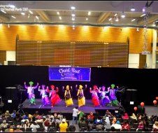 A group of people are dancing on a stage in front of a crowd.