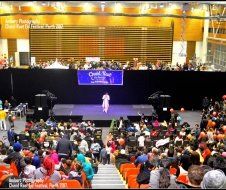 A large group of people are sitting in a large auditorium watching a performance.