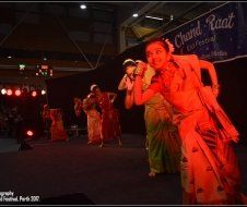 A group of women are dancing on a stage in front of a sign that says chand raat.