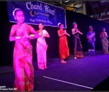 A group of young girls are dancing on a stage at a festival.