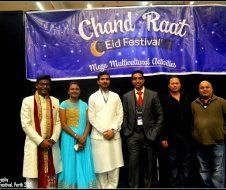 A group of people are posing for a picture in front of a banner that says chand raat eid festival.