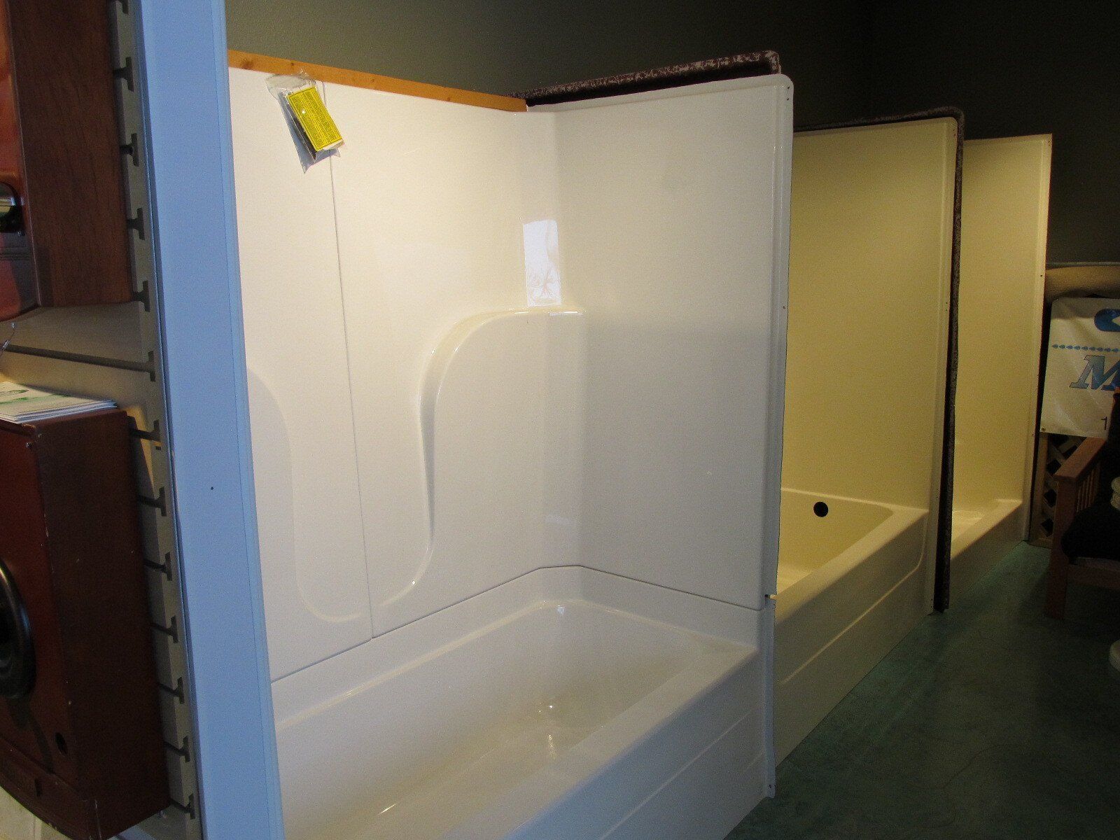 White shower stall in a room with beige walls and a green floor.