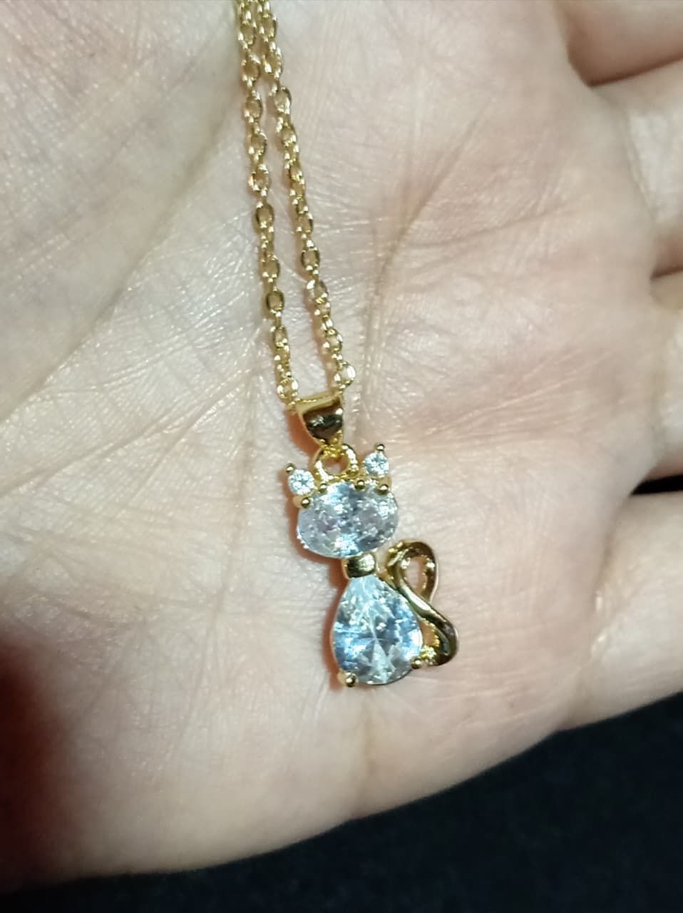Collar de oro con colgante en forma de lágrima con una gema transparente sobre fondo oscuro.