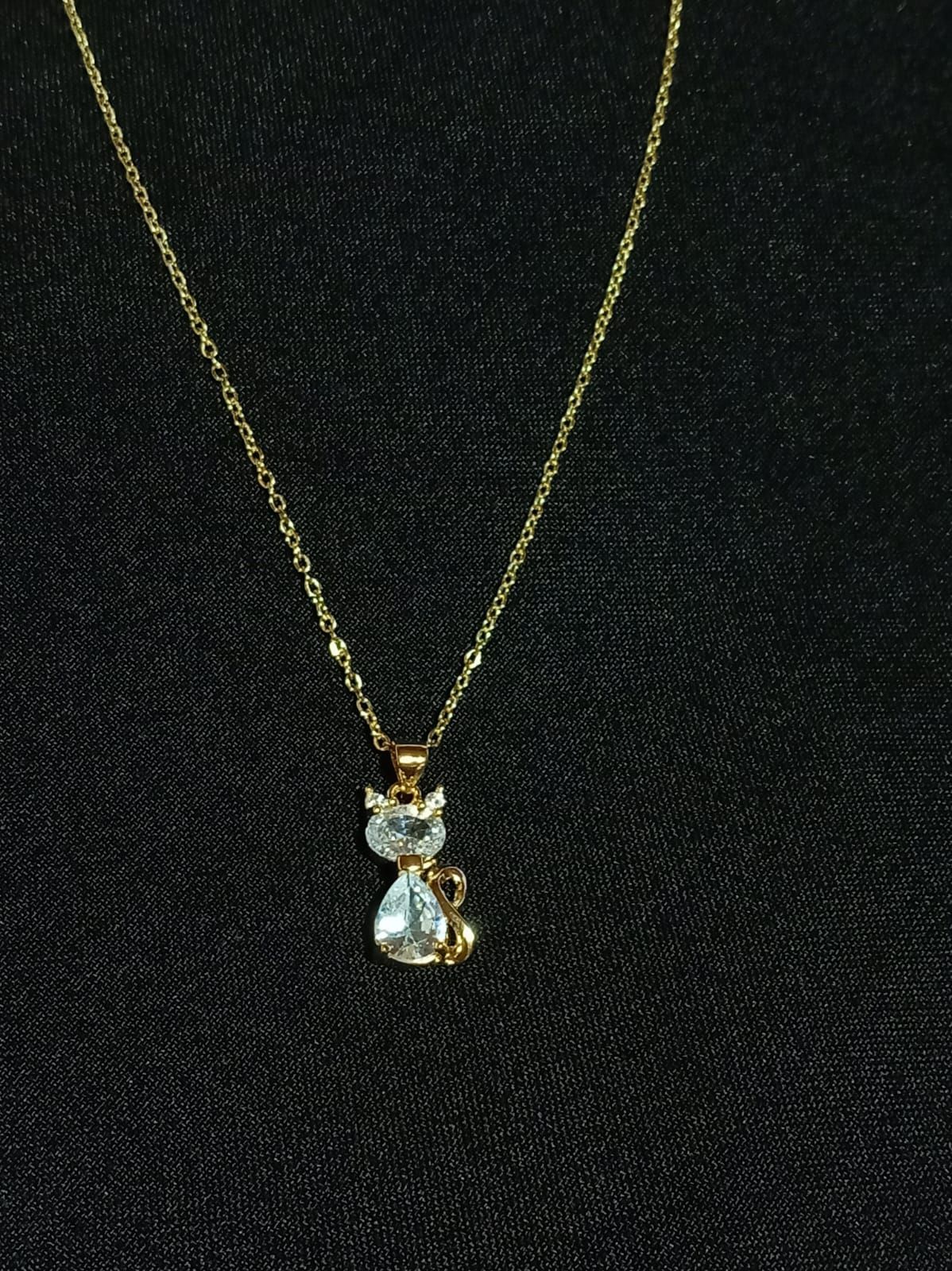 Collar de oro con colgante en forma de lágrima con una gema transparente sobre fondo oscuro.