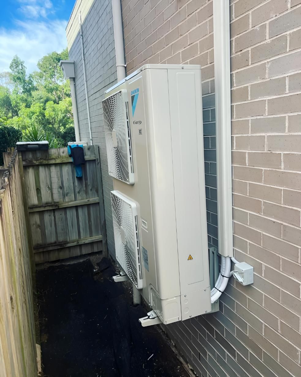 White Air Conditioner is Sitting on the Brick Building — Kiama Air Conditioning in Albion Park Rail, NSW