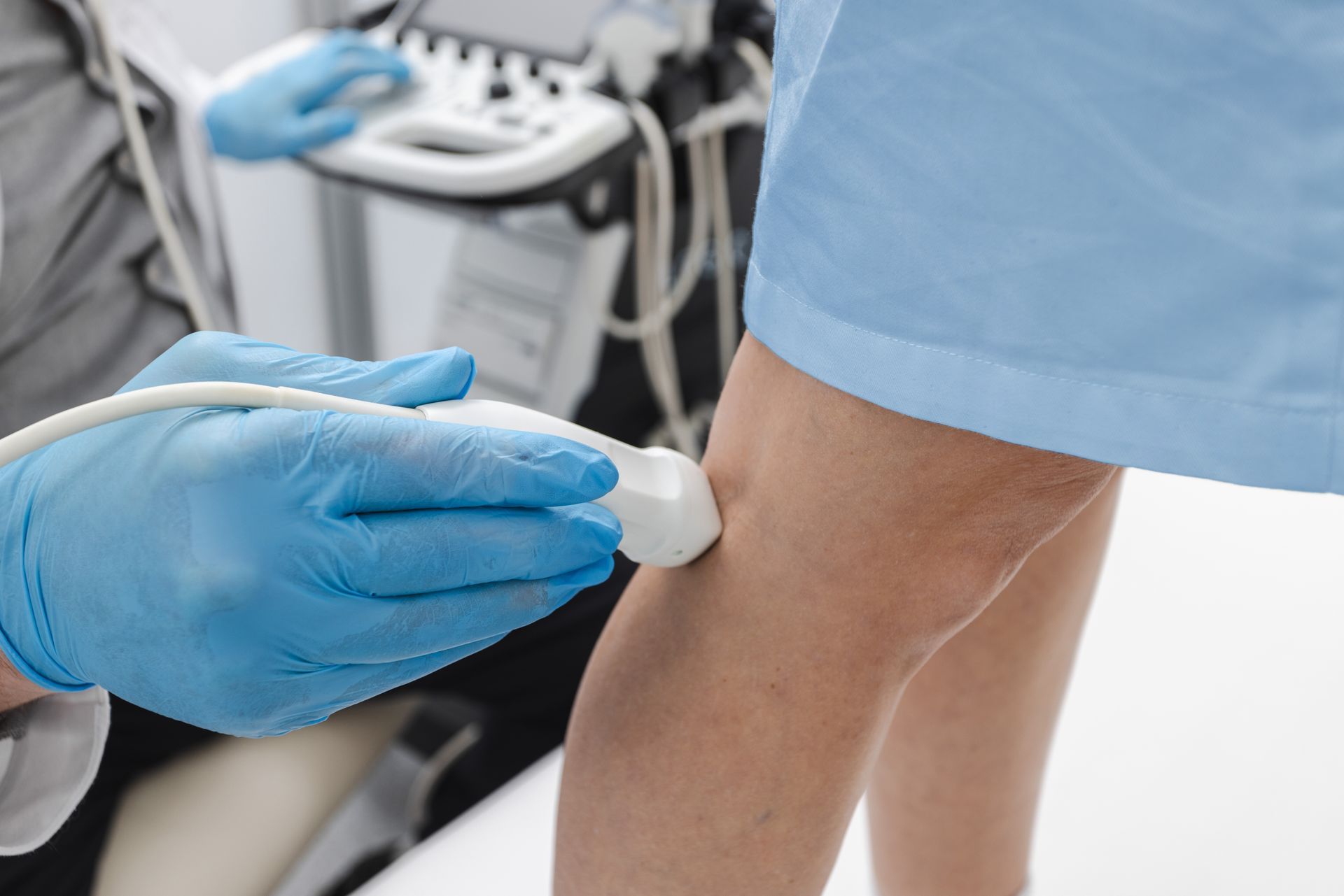 A medical professional using an ultrasound device on a patient's leg.