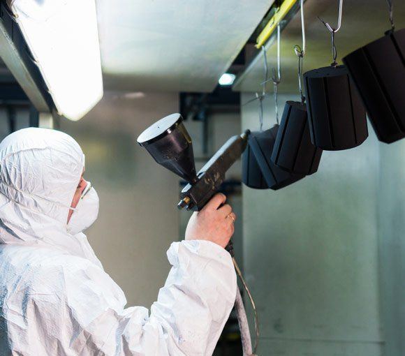 Man in a Protective Suit Sprays Powder Paint — Powder coating service in Scone, NSW