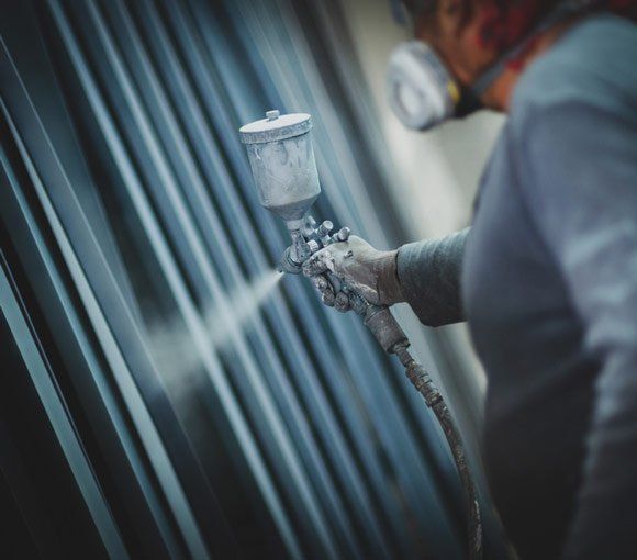 Man Painting Metal Products with a Spray Gun — Powder coating service in Gosford, NSW