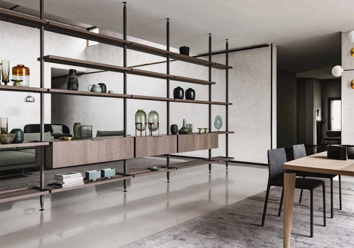 Soggiorno open space con un'ampia scaffalatura con oggetti decorativi, un tavolo da pranzo e sedie.