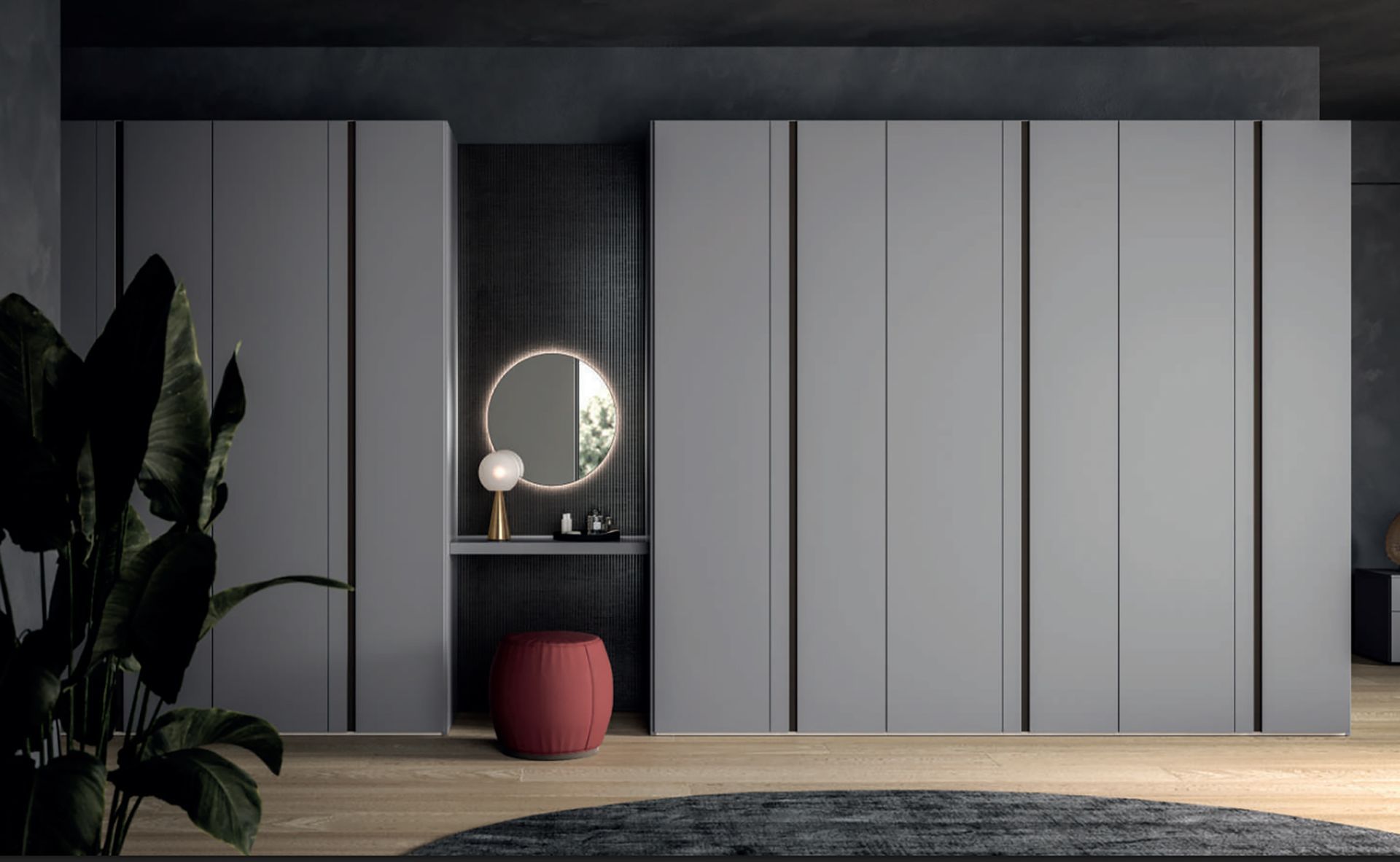 Armadio moderno grigio con specchio rotondo illuminato, piccola mensola, sgabello rosa e pianta in una stanza elegante.