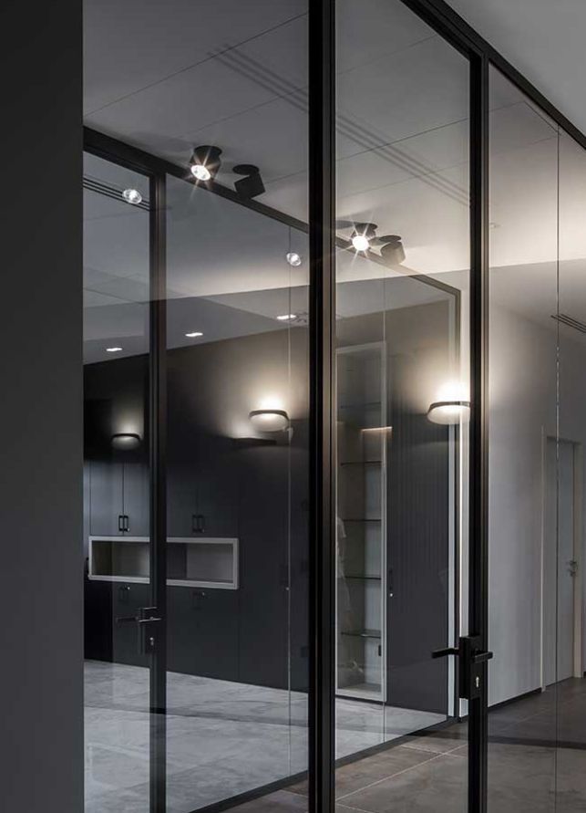 Moderno ingresso per ufficio in vetro con porte con telaio nero e pareti interne bianche.