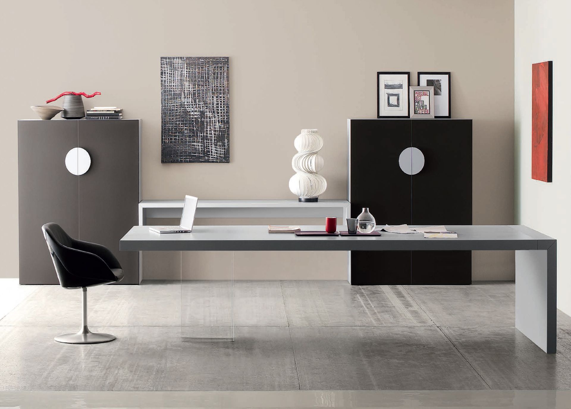 Ufficio moderno con scrivania grigia, armadietti, sedia, opere d'arte e accessori.