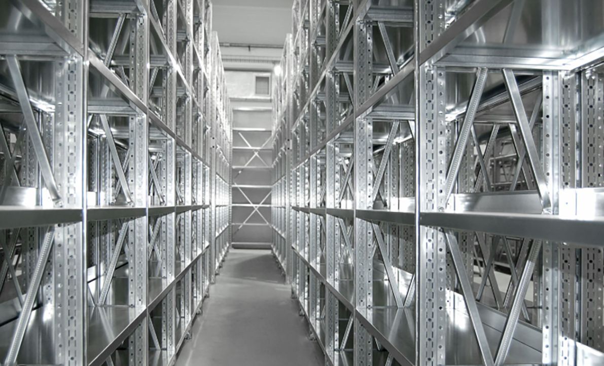 File di scaffalature metalliche in un magazzino o in un deposito, che creano corridoi.