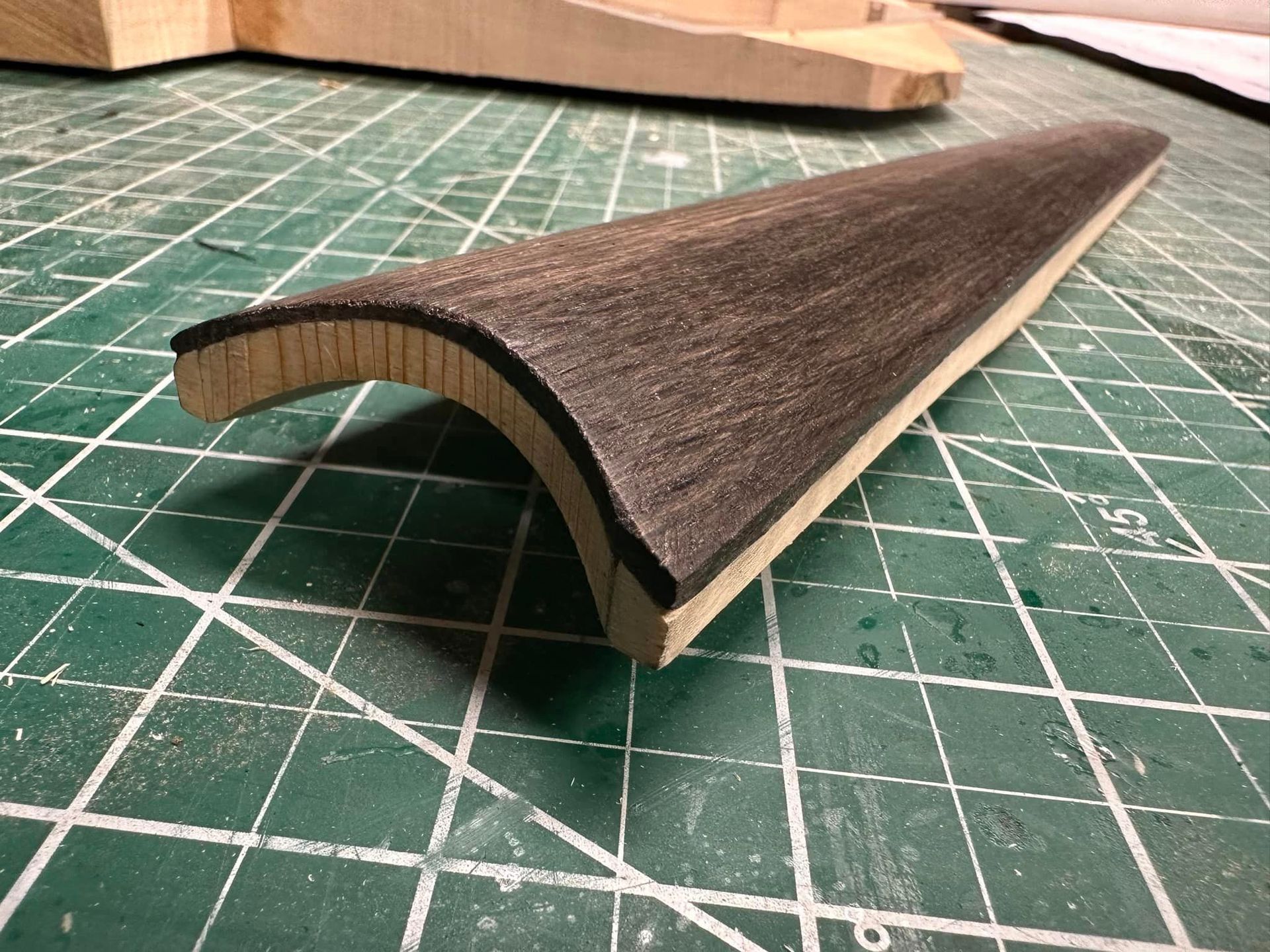 A piece of wood is sitting on a green cutting mat