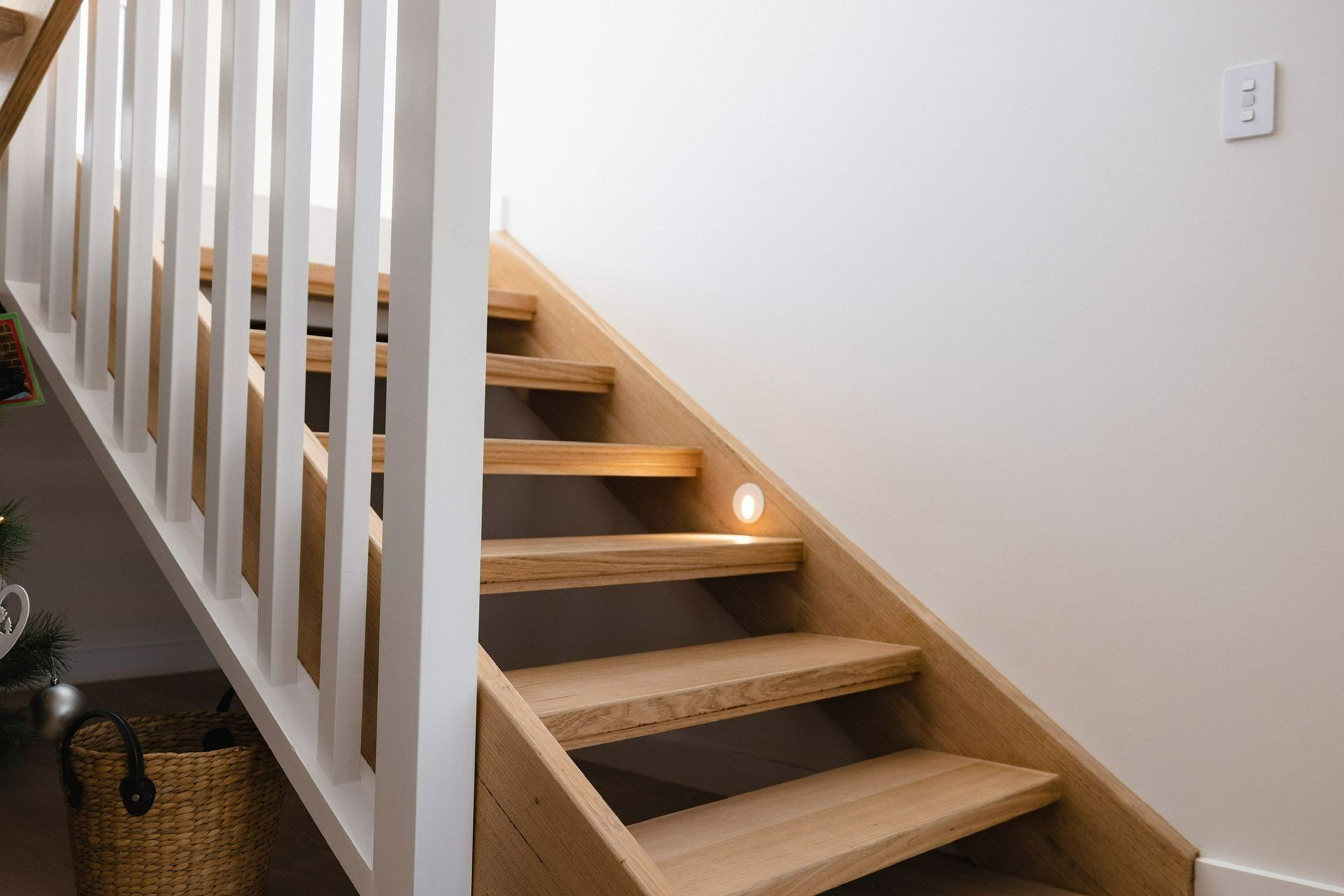 A Wooden Staircase with A White Railing and A Light on The Steps — Blue Horizon Projects in Berkeley Vale, NSW