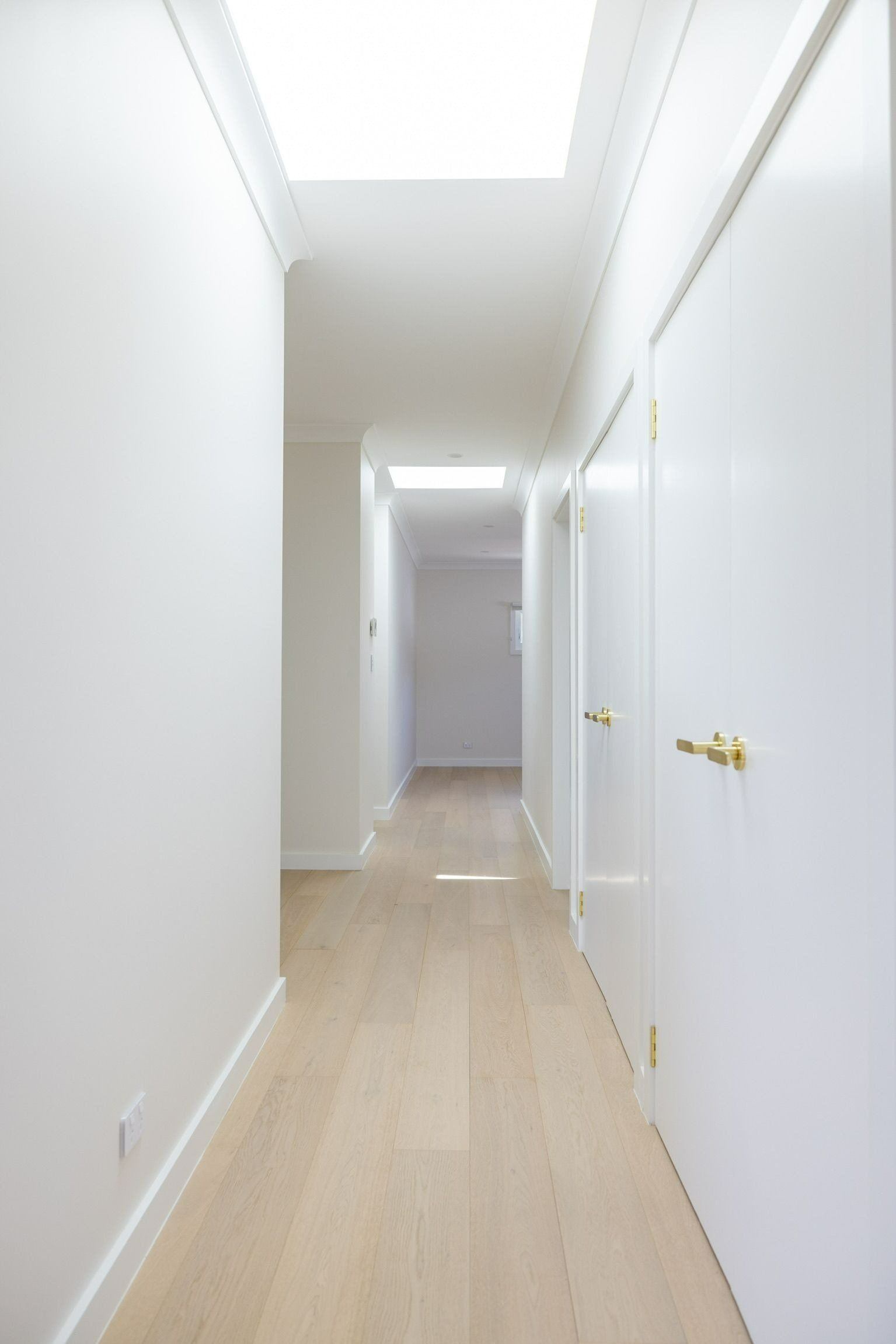 A Long Hallway with White Walls and Wooden Floors in A House — Blue Horizon Projects in Berkeley Vale, NSW