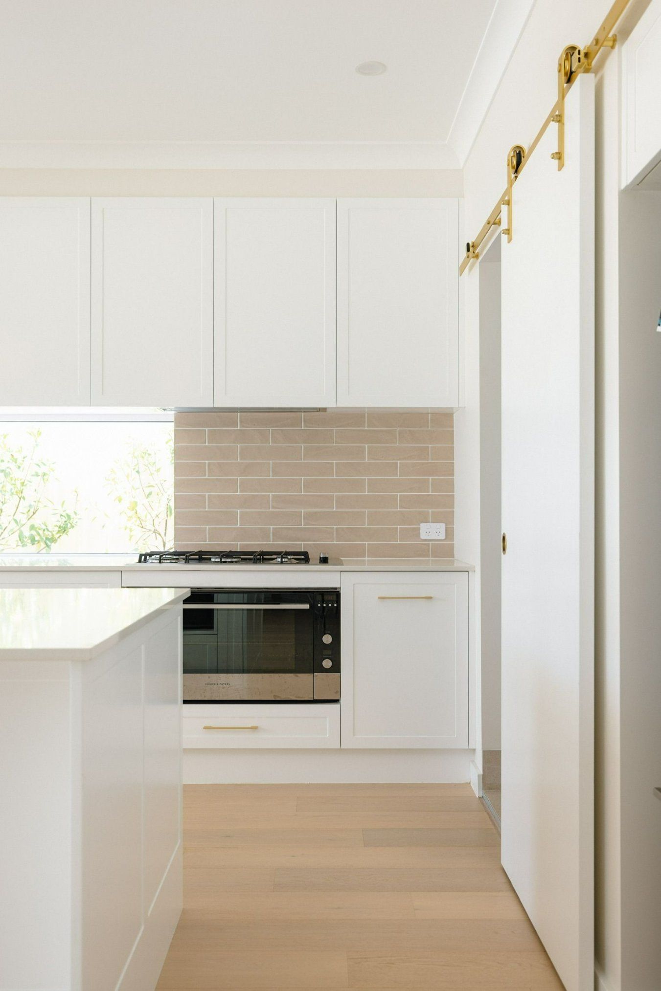 A Kitchen with White Cabinets , a Stove , and A Sliding Barn Door — Blue Horizon Projects in Long Jetty, NSW