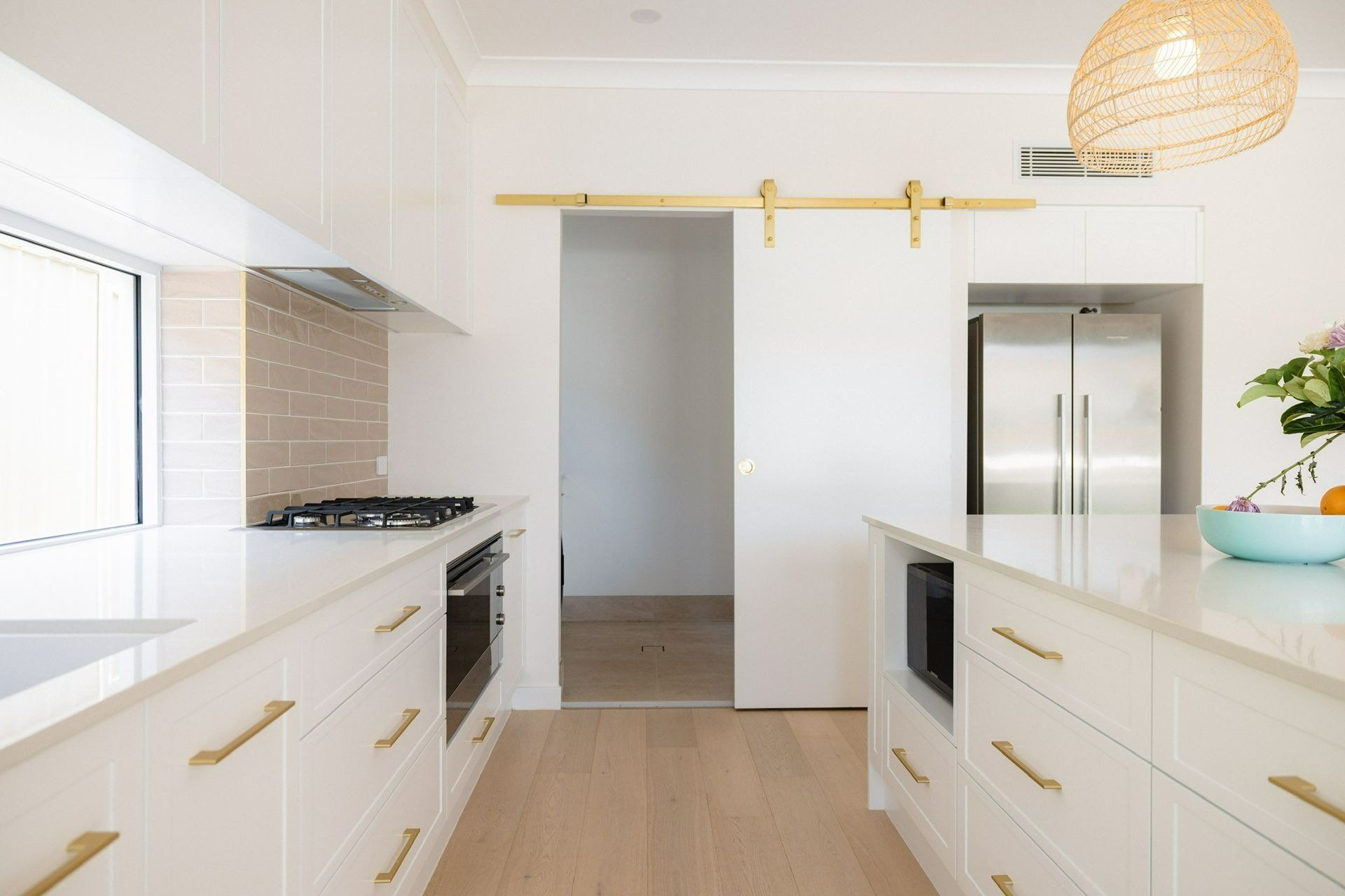 A Kitchen with White Cabinets and A Sliding Barn Door — Blue Horizon Projects in Forresters Beach, NSW