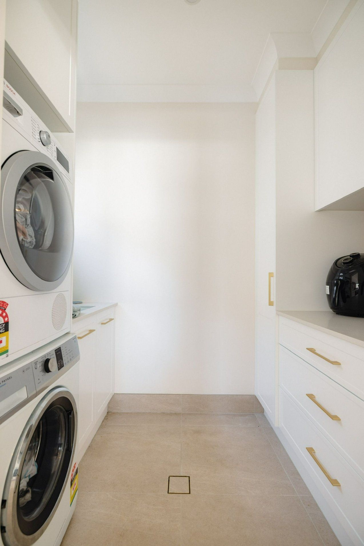 A Laundry Room with A Washer and Dryer Stacked on Top of Each Other — Blue Horizon Projects in Forresters Beach, NSW