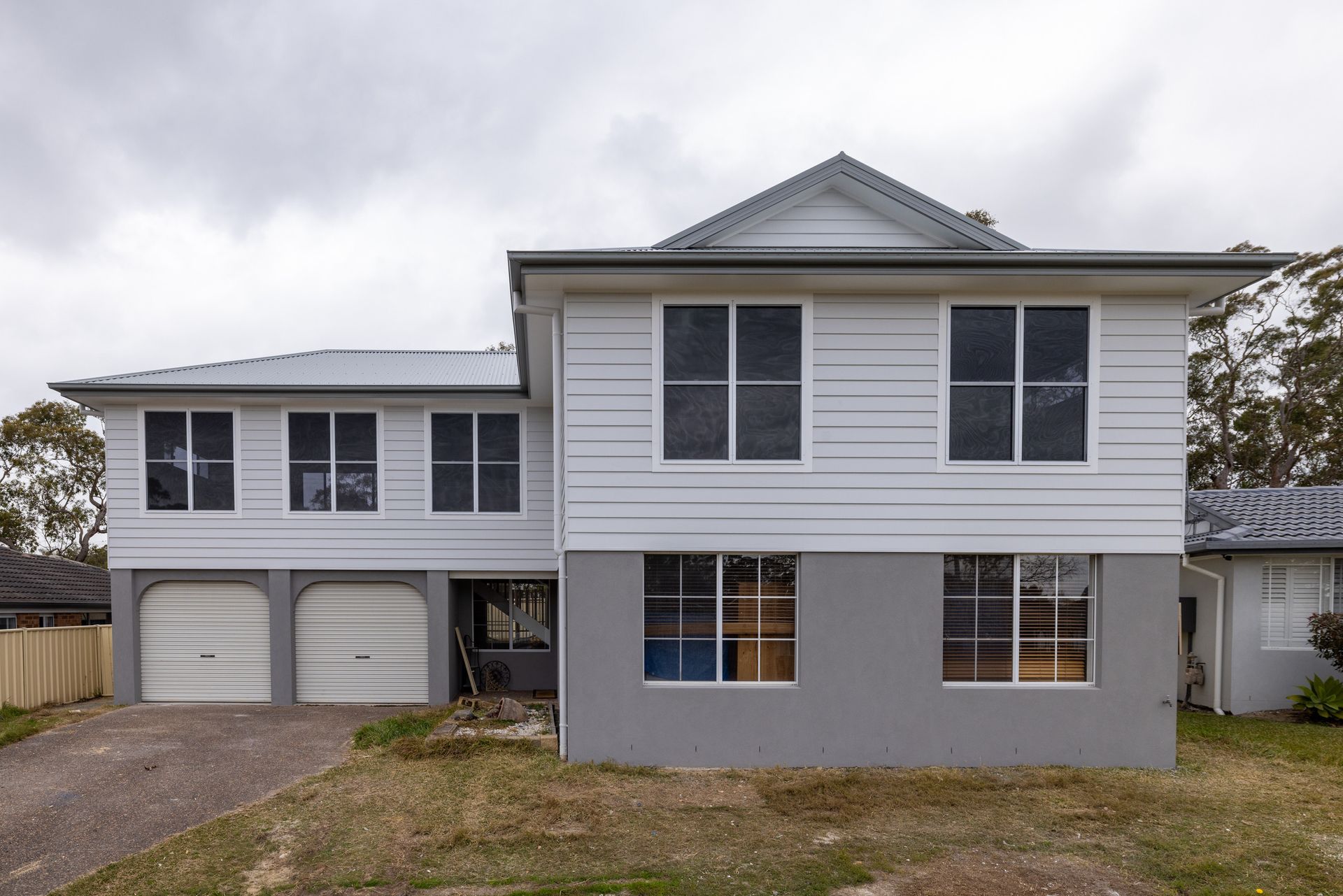 A Modern House with A Large Garage Door and A Driveway — Blue Horizon Projects in Bateau Bay, NSW