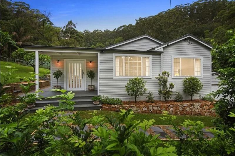 A Small White House Is Sitting on Top of A Hill Surrounded by Trees — Blue Horizon Projects in Bateau Bay, NSW