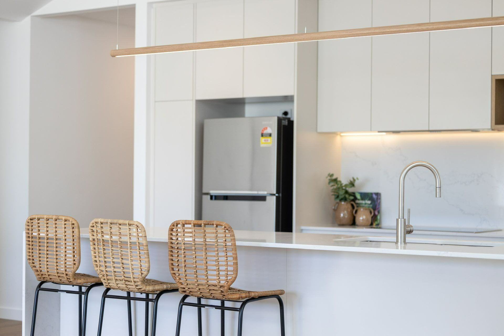 A Kitchen with White Cabinets and Wicker Chairs — Blue Horizon Projects in Lake Macquarie, NSW