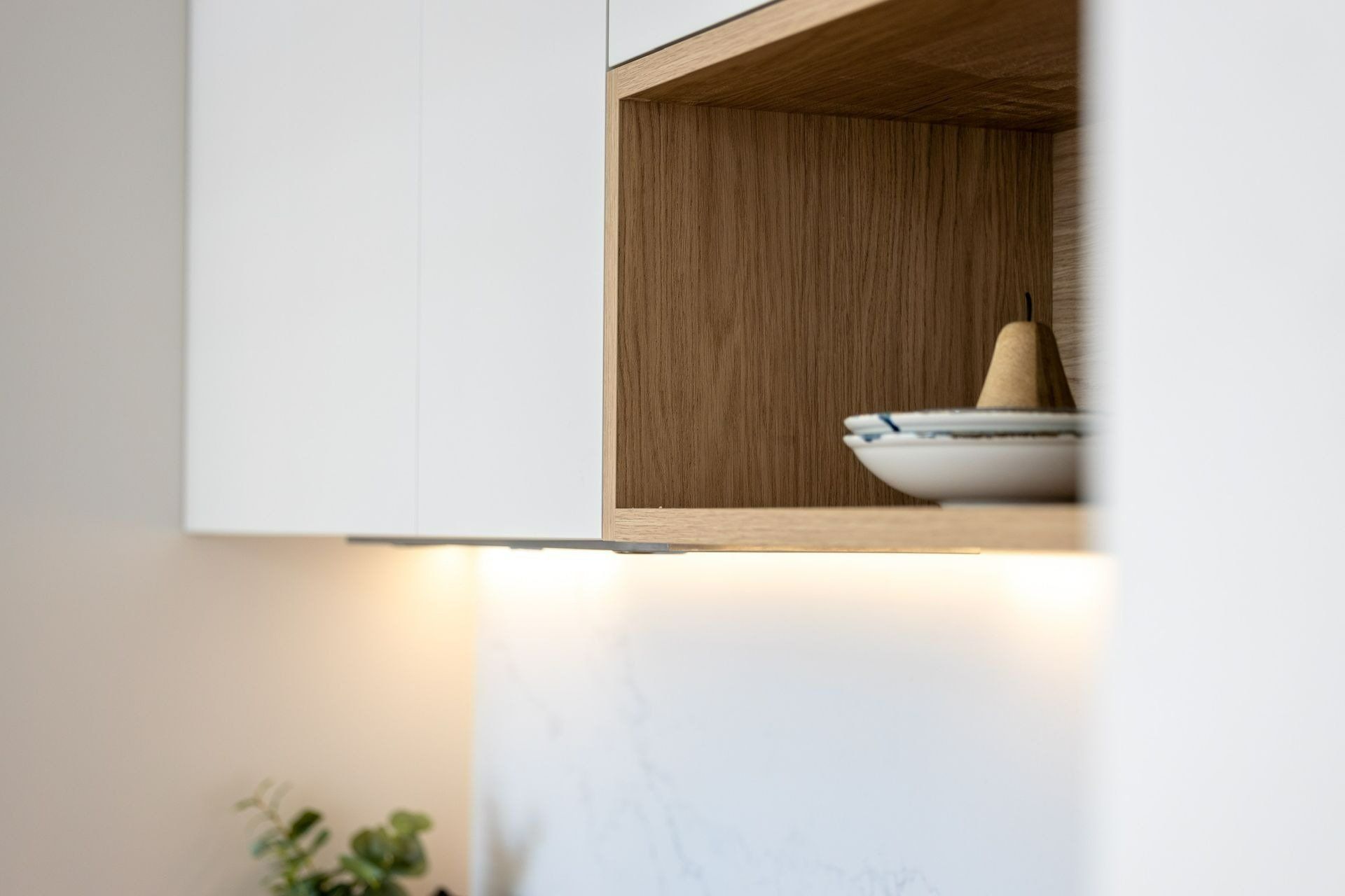 A Kitchen with White Cabinets and A Wooden Shelf with A Bowl on It — Blue Horizon Projects in Shelly Beach, NSW