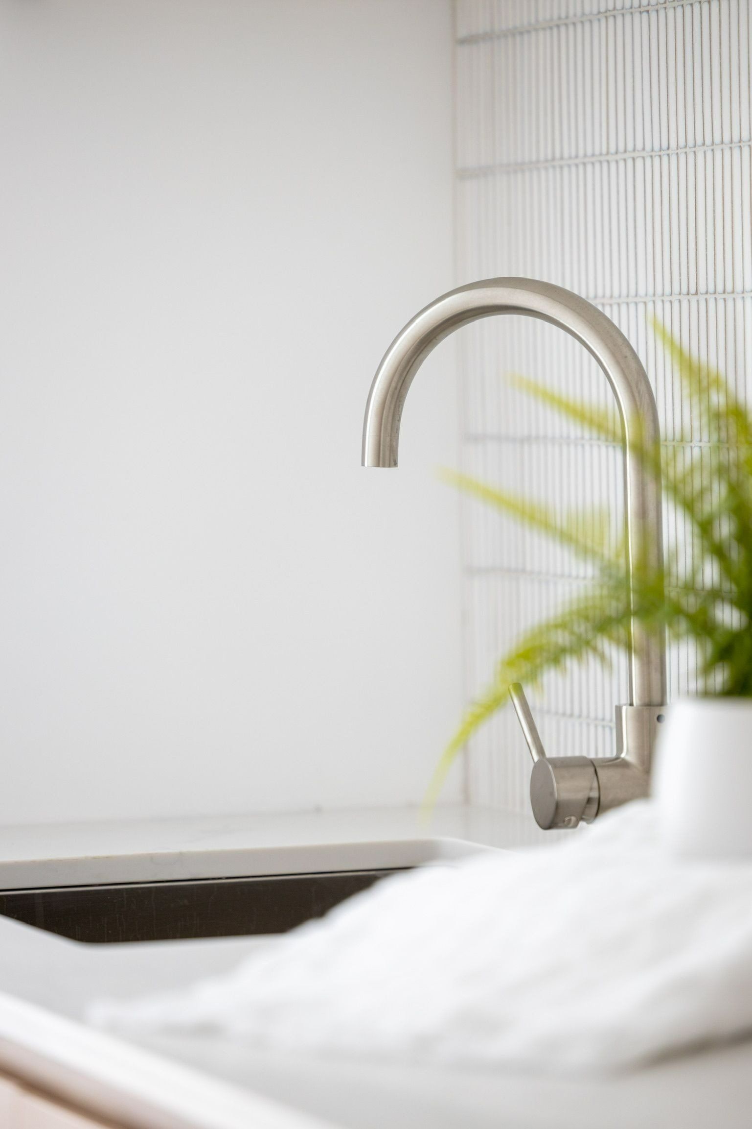 A Kitchen Sink with A Faucet and A Plant — Blue Horizon Projects in Blue Bay, NSW
