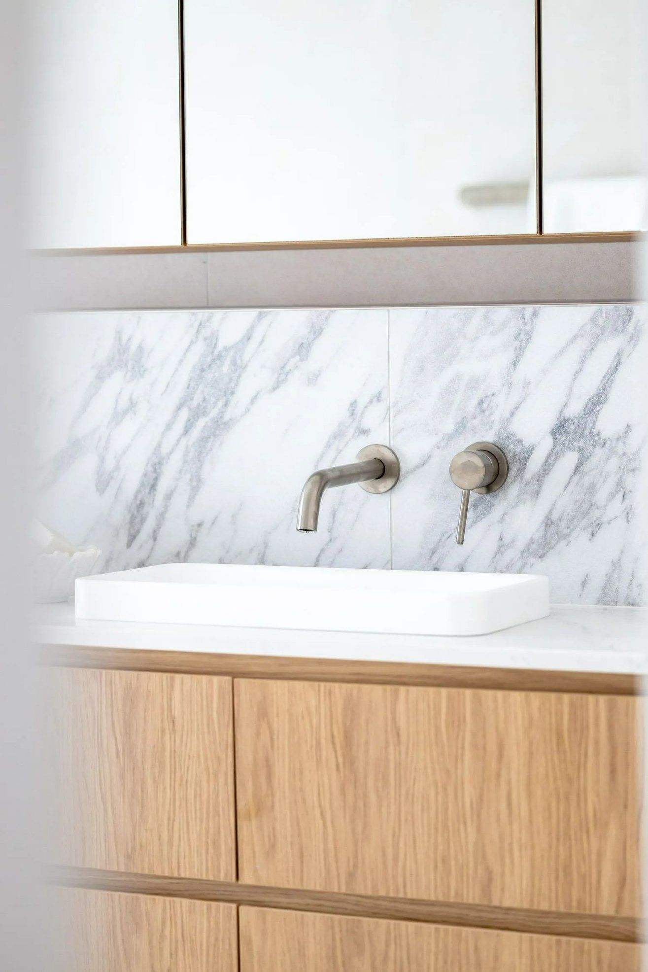 A Bathroom Sink with A Marble Wall and Wooden Cabinets — Blue Horizon Projects in Toowoon Bay, NSW